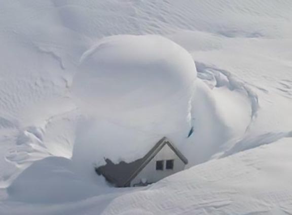 maison ensevelie sous la neige qui a besoin d'un déneigeur